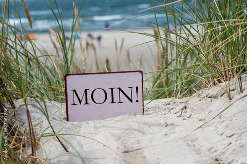 Sign with the German dialect word 'Moin' (Hello) in the sand dunes of an German island in the north sea. photo