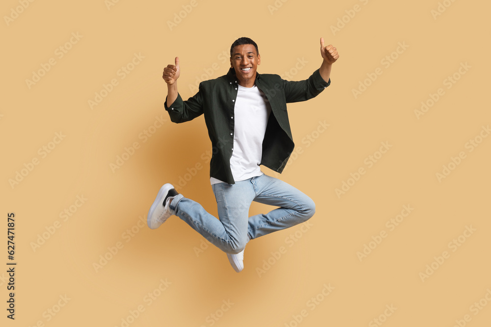Happy black man jumping up and showing thumb ups