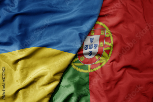 big waving national colorful flag of ukraine and national flag of portugal .