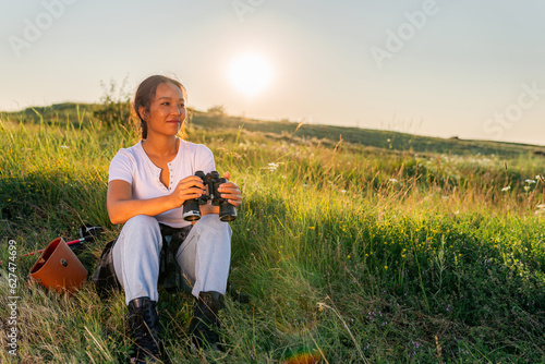 A young adventurer uses binoculars as she walks through the fields and watches birds