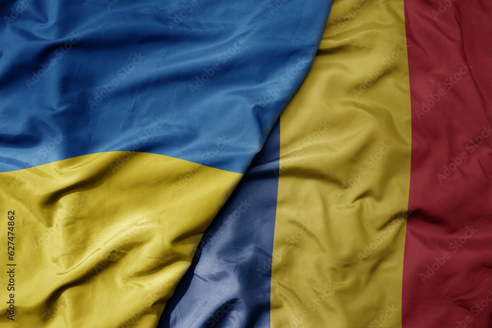 big waving national colorful flag of ukraine and national flag of romania . big waving national colorful flag of ukraine and national flag of romania .