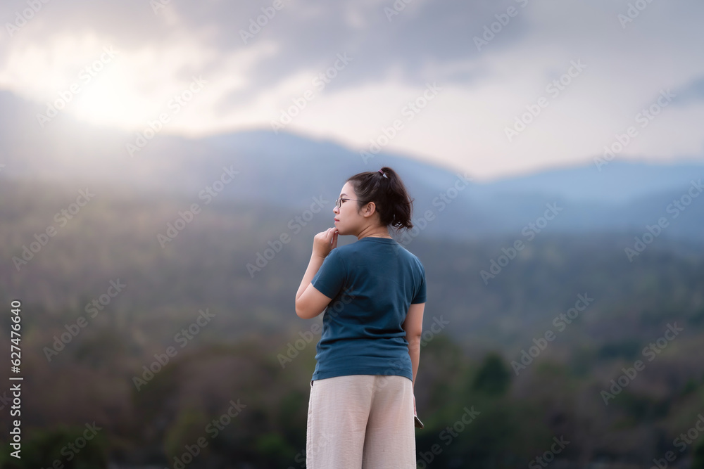 Naklejka premium Happy Relaxing Portrait asian woman Wear dark green dress while stand on green grass lawn beside a reservoir at the city park evening twilight time outdoors.
