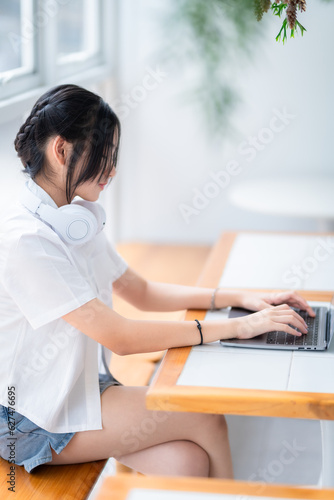 Happy of cute smiles Asian of attractive young Cute girl little wearing headphones and listening music using laptop computer working from at the cafe.Online education  elearning concept.