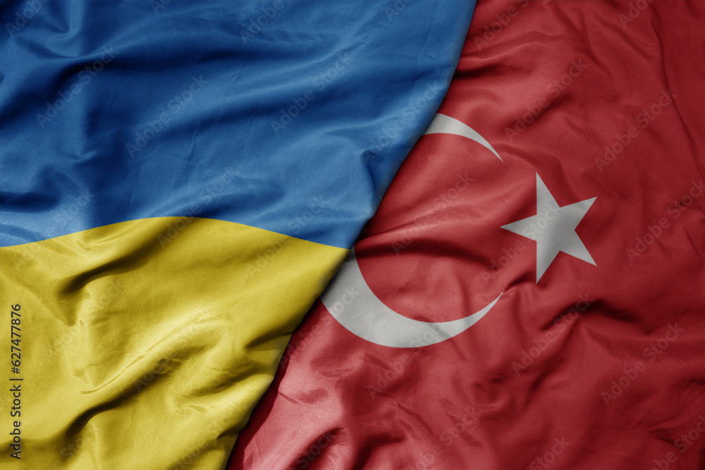 Fototapeta premium big waving national colorful flag of ukraine and national flag of turkey .
