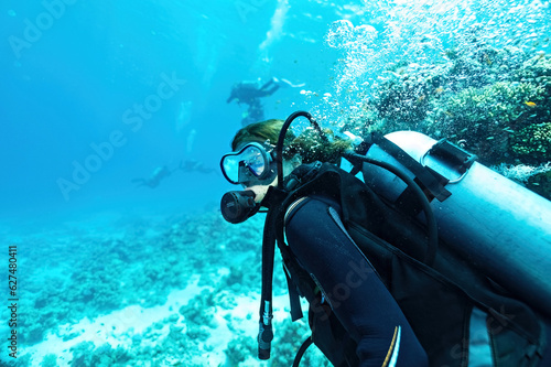 Woman diver in sun rays with corals on background in Egypt