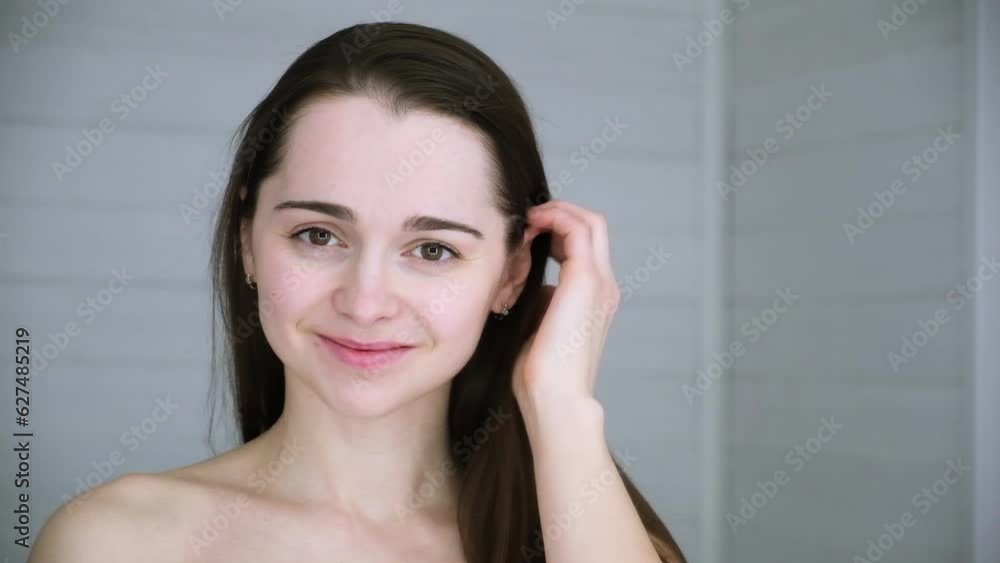 Beautiful smiling 30s woman fixes her hair with hands. A girl gets ready in the morning. Undyed brunette long straight hair. Without makeup. Beauty model. Healthy appearance hair and skin. Lifestyle. Beautiful smiling 30s woman fixes her hair with hands. A girl gets ready in the morning. Undyed brunette long straight hair. Without makeup. Beauty model. Healthy appearance hair and skin. Lifestyle.