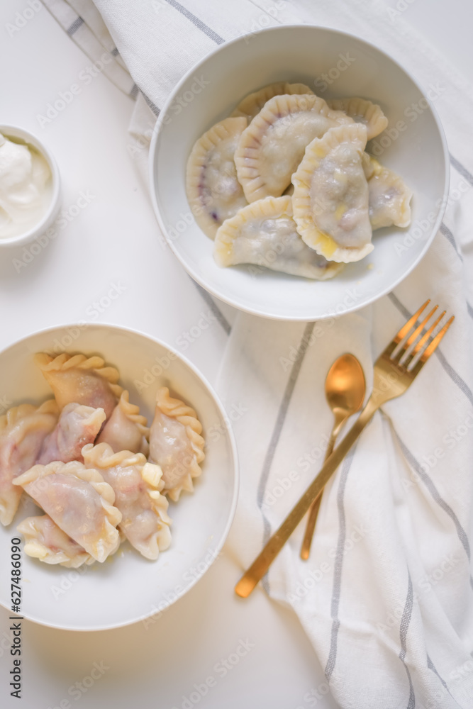 delicious food on the table. delicious homemade Ukrainian dumplings with various berries, two white bowls with golden fork and spoon beside delicious food on the table. delicious homemade Ukrainian dumplings with various berries, two white bowls with golden fork and spoon beside