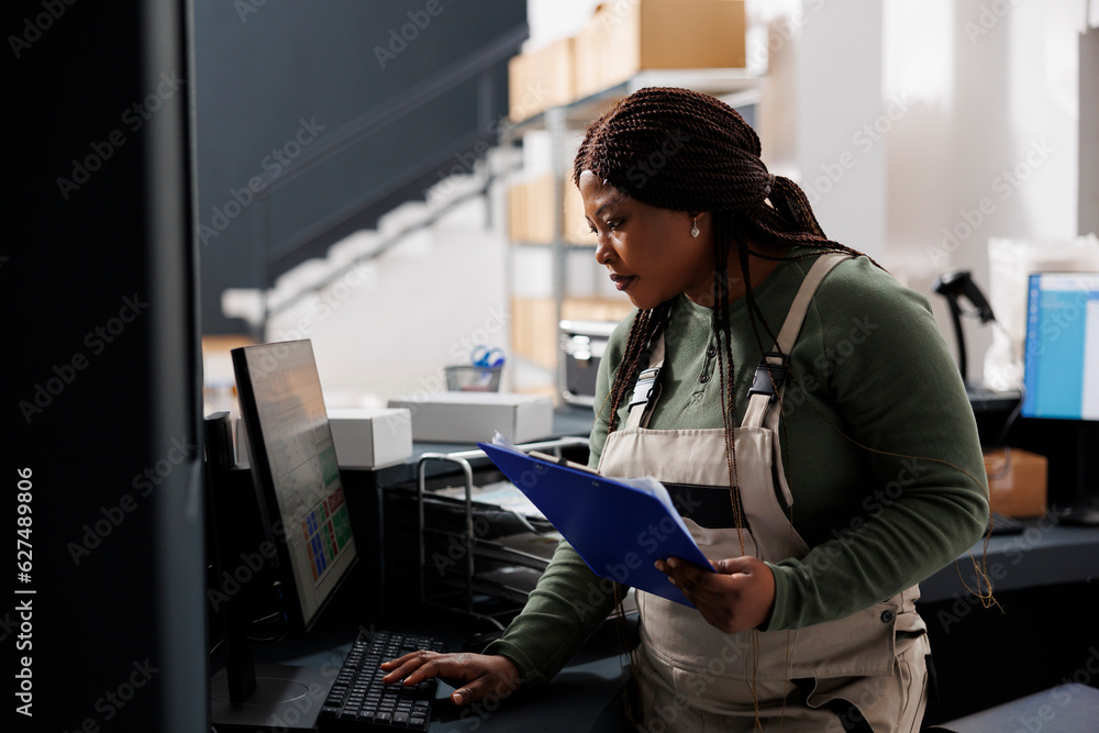 © DC Studio - Stockroom supervisor looking at inventory report on computer, working at merchandise quality control in warehouse. African american employee preparing customers orders for shipping in storehouse