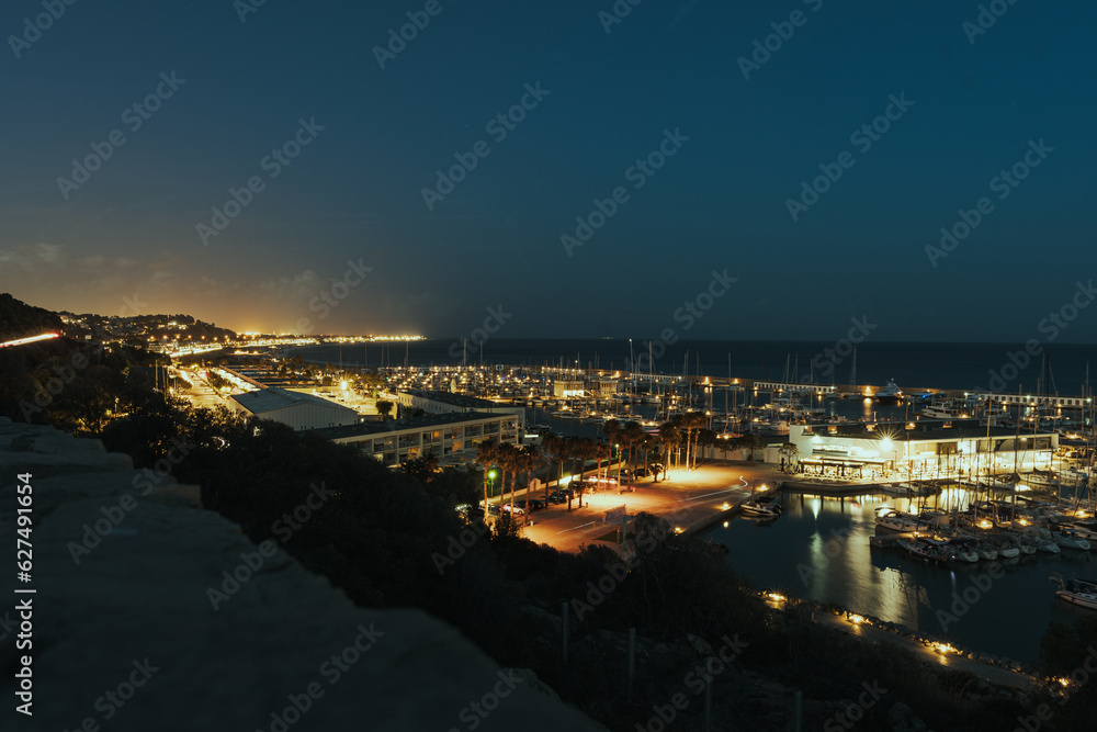 Mountain view of a maritime headland night city in Barcelona with lights and boats and restaurants