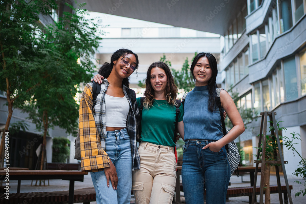 Portrait of three college student girls looking at camera. They are at the university.