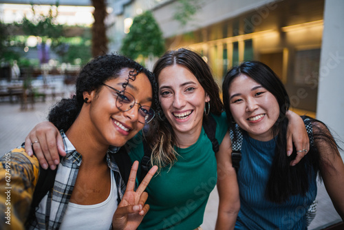 Three college student girls taking a selfie at the university campus during a class break.