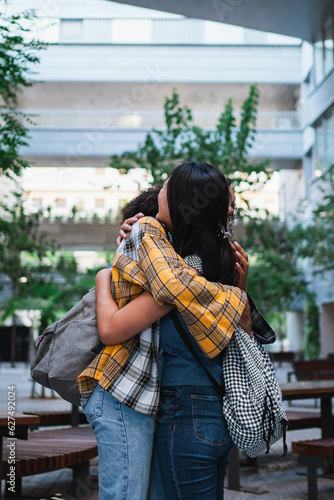 Two friends hugging each other at the university campus. They just got back to school after summer.