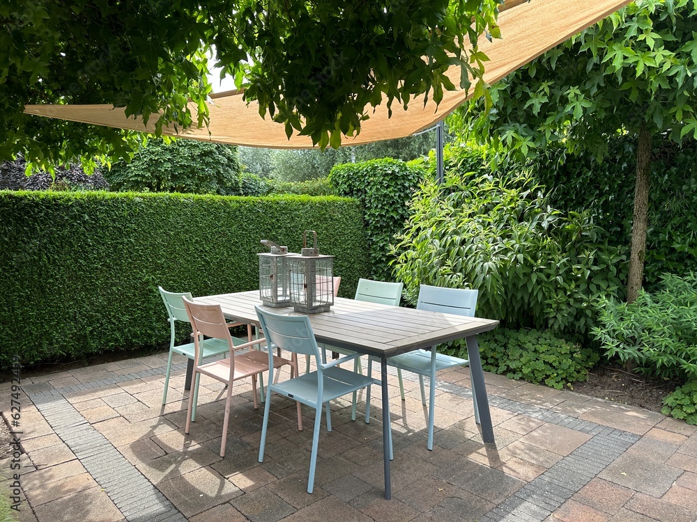 Appeltern, Netherlands, July 11, 2023: Appeltern adventure garden. Beautiful summer terrace with shade sail, garden chairs and wooden table