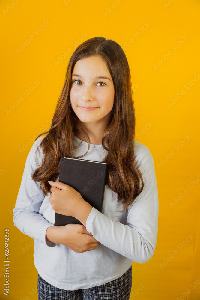 Little cute girl schoolgirl holding notepad book in her hands Little cute girl schoolgirl holding notepad book in her hands