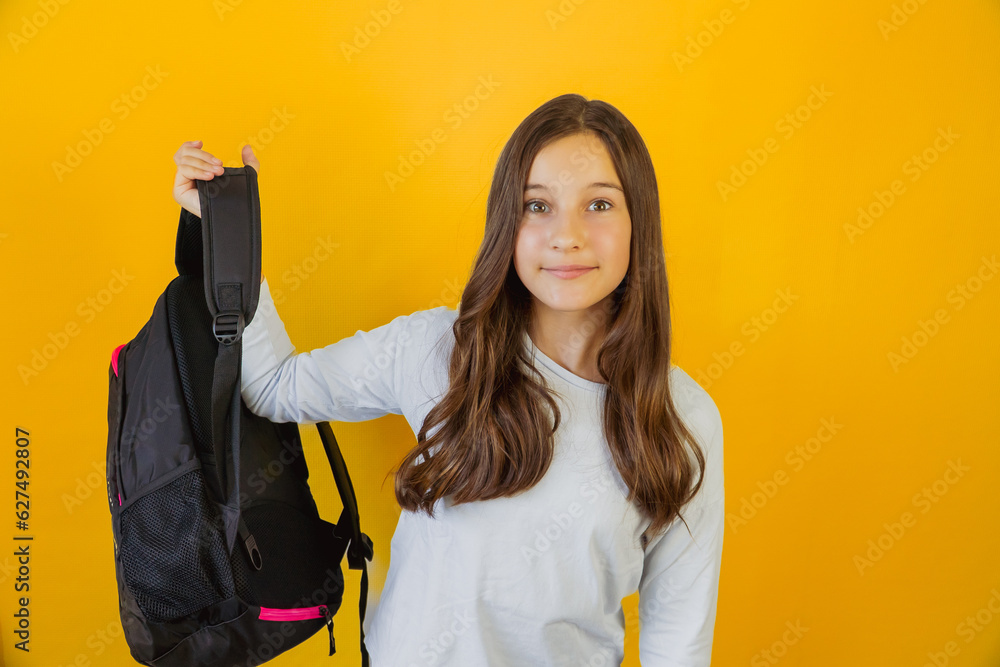 Little cute girl schoolgirl joyfully holds school backpack in her hand