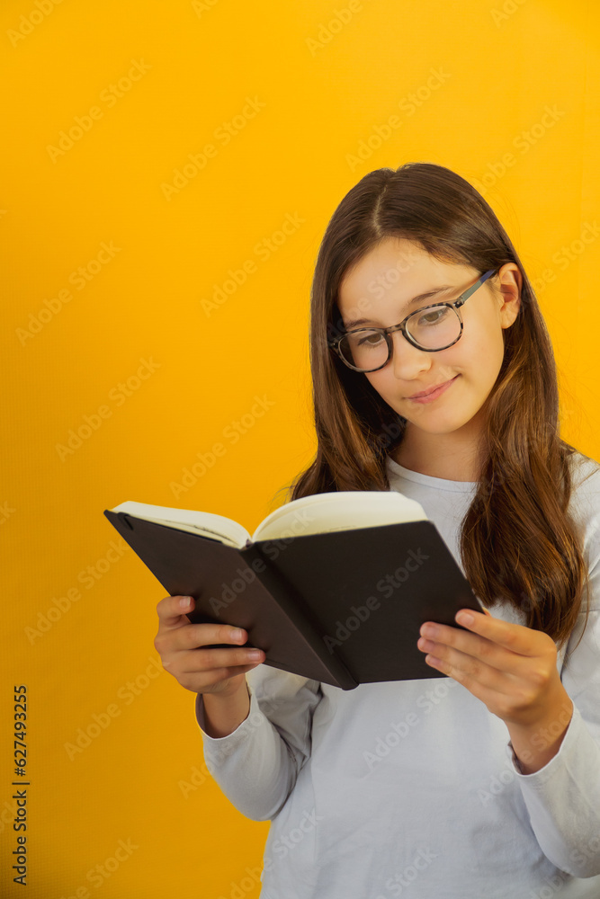Little lovely girl in glasses holds notepad book in her hands Little lovely girl in glasses holds notepad book in her hands
