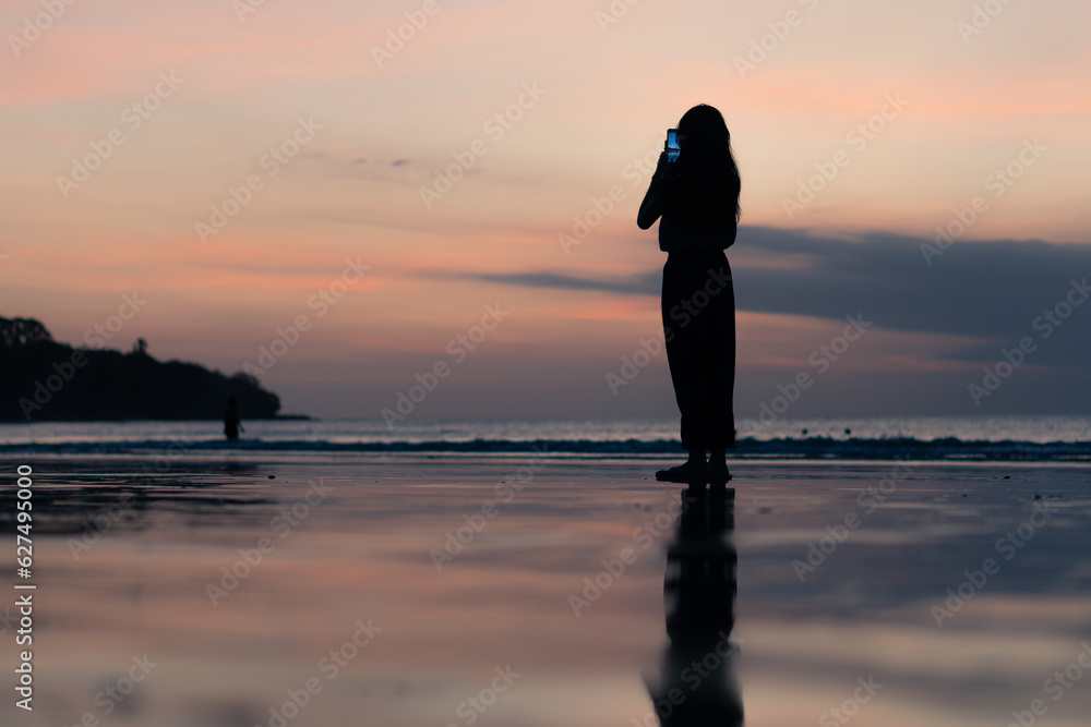 people using smart phone for taking a sunset photo at the beach