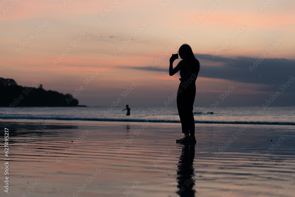 people using smart phone for taking a sunset photo at the beach