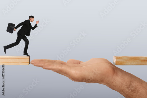 Support or partnership concept. Man making bridge with his hand between wooden blocks to help running businessman