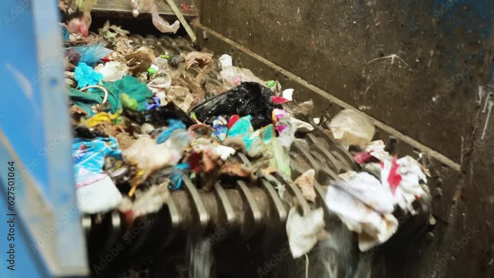 Garbage falls and moves along the trash shredder for recycling at a waste disposal factory