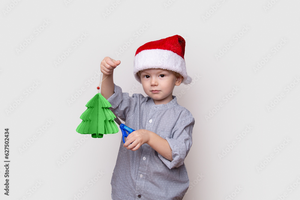a little fair-haired boy in a shirt and a santa claus hat celebrates new year and christmas, white background, the child rejoices, childhood, holiday, gift, fun, winter a little fair-haired boy in a shirt and a santa claus hat celebrates new year and christmas, white background, the child rejoices, childhood, holiday, gift, fun, winter