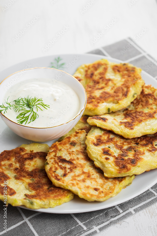 Zucchini pancakes with cream sauce on plate. Healthy diet food. Dinner table setting.