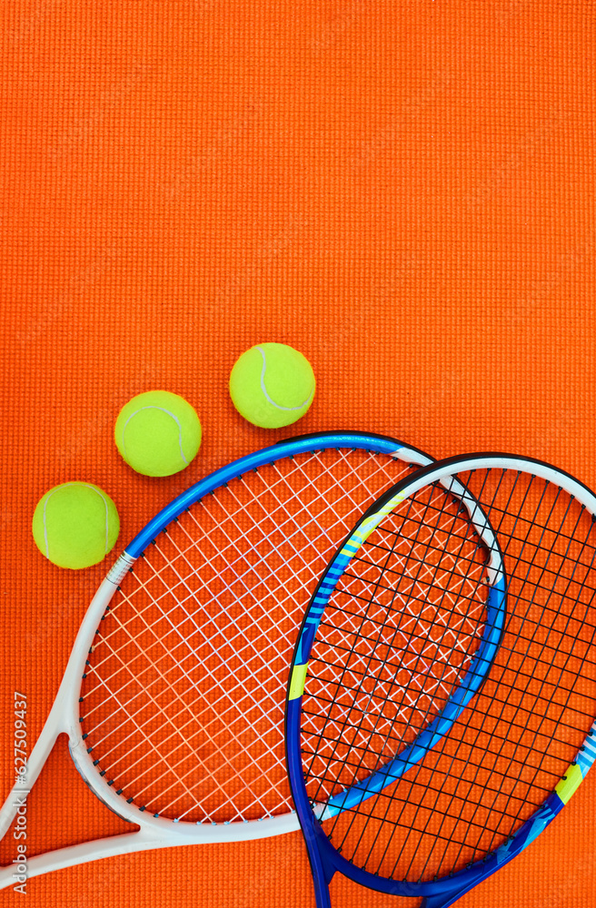 Who wants to serve. High angle shot of tennis essentials placed on top of an orange background inside of a studio.