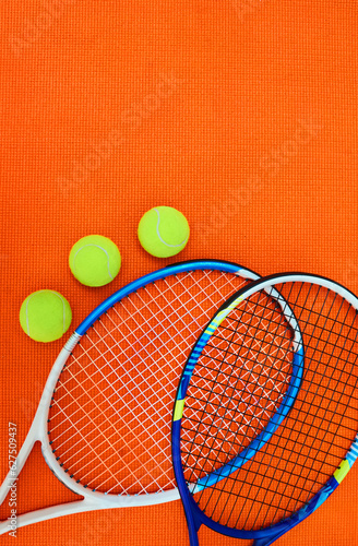 Who wants to serve. High angle shot of tennis essentials placed on top of an orange background inside of a studio. © Thaakirah/peopleimages.com