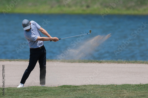 golf player hitting the ball on sand trap