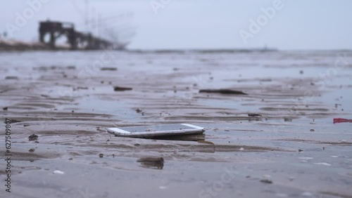 Wallpaper Mural Smartphone falls on the ground on the wet beach Torontodigital.ca