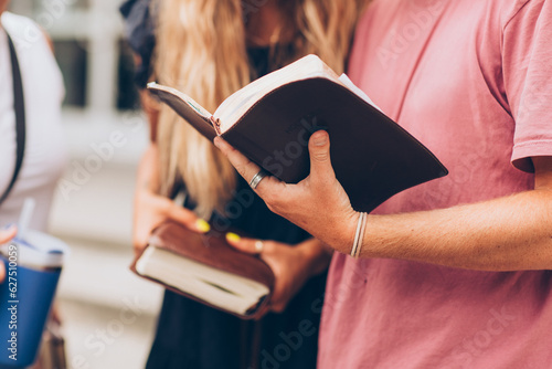 cropped photo of young adults youth talking while holding their bibles leather journal notebook books school college library