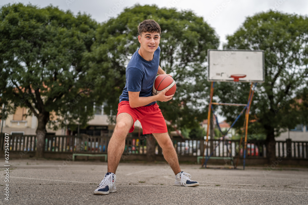 Obraz premium One caucasian teenager stand on basketball court with ball