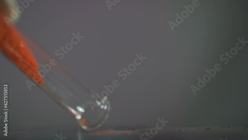 Orange crystal-like powder hangs from the test tube. Slow motion