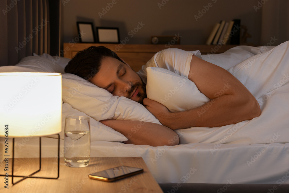 © New Africa - Handsome man sleeping in bed at night