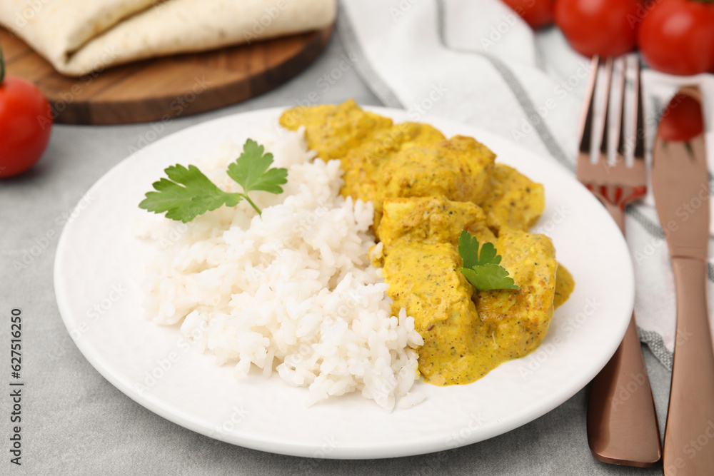 Delicious rice and chicken with curry sauce on light grey table, closeup