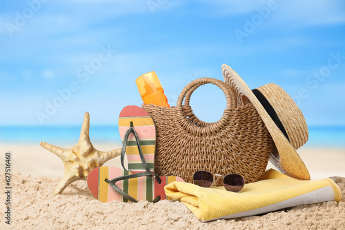 Bag with sunscreen and accessories on sunny ocean beach. Summer vacation