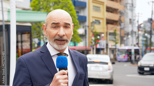 A Caucasian male reporter broadcasting on television in a local city. photo