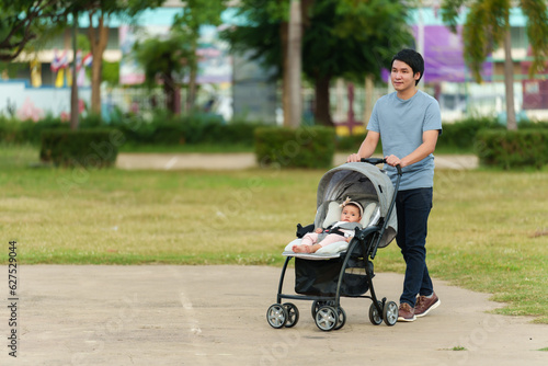 Картината върху платно happy father pushing infant baby stroller and walking in park