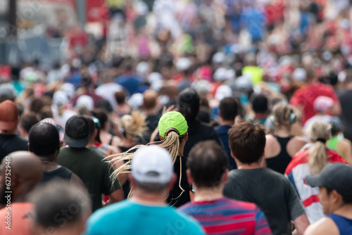 Lone neon green hat stands out in massive crowd of runners at major 10K event.