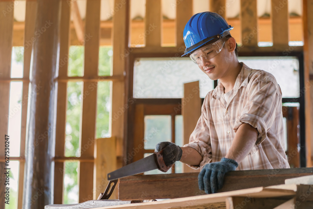 Asian carpenter smiling happily working on his desk at construction design wearing a hat and glasses Asian carpenter smiling happily working on his desk at construction design wearing a hat and glasses