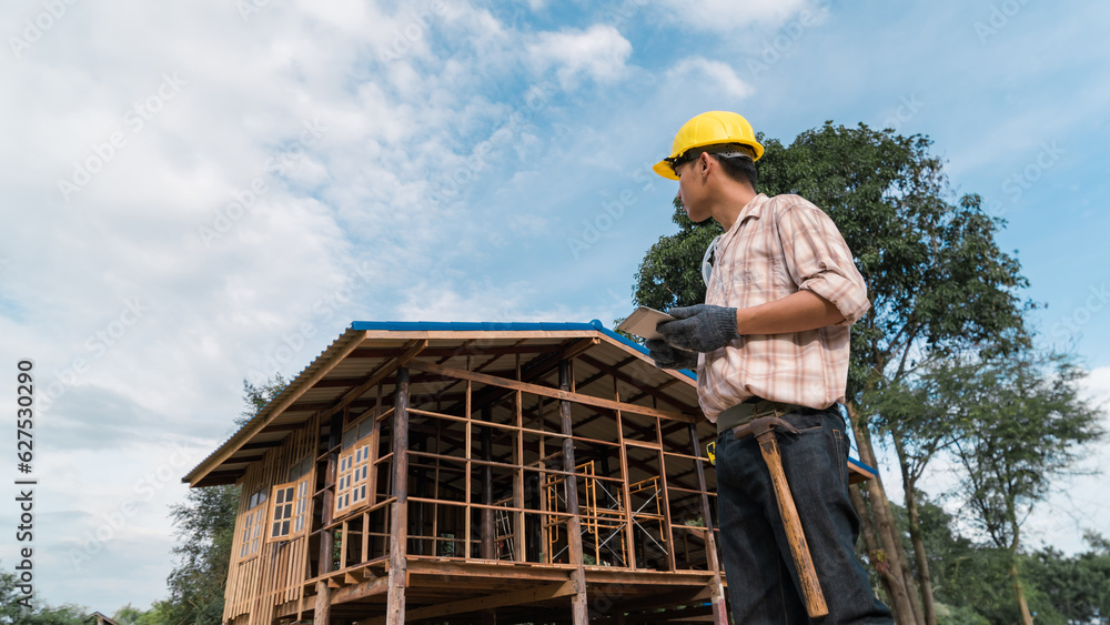 Asian carpenter holding tablet working at construction site using technology Wear a helmet and goggles to prevent dust. Asian carpenter holding tablet working at construction site using technology Wear a helmet and goggles to prevent dust.