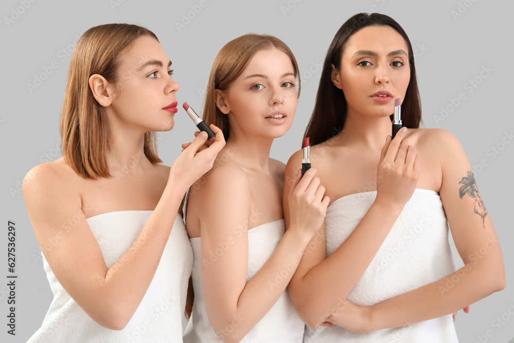 Young women with lipsticks on grey background