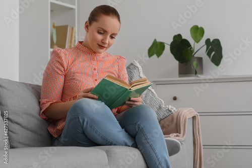 Young woman reading book on...