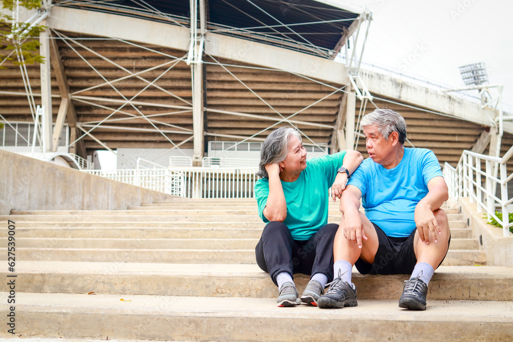 Asian elderly couple exercising outdoors together Sit down and rest on the stairs. concept of living in retirement, senior health care. copy space