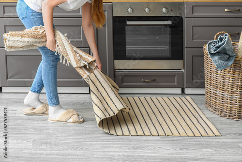 Foto Woman placing rug on floor in modern kitchen