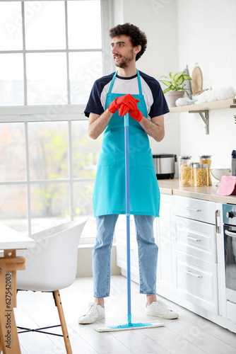 Young man mopping floor in ...