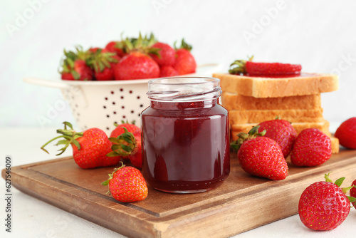 Jar of sweet strawberry jam and fresh berries on table