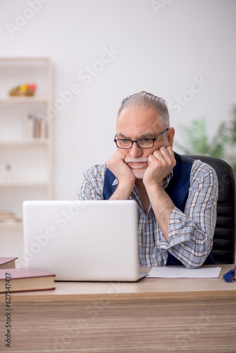 Old male writer sitting at workplace