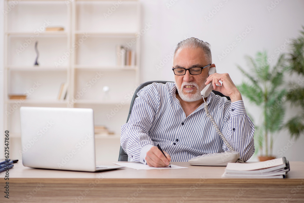 Old male employee working in the office Old male employee working in the office