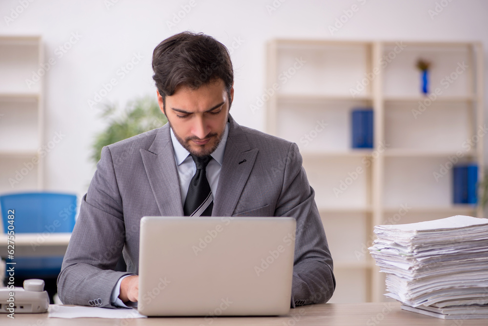 Young male employee and too much work in the office Young male employee and too much work in the office